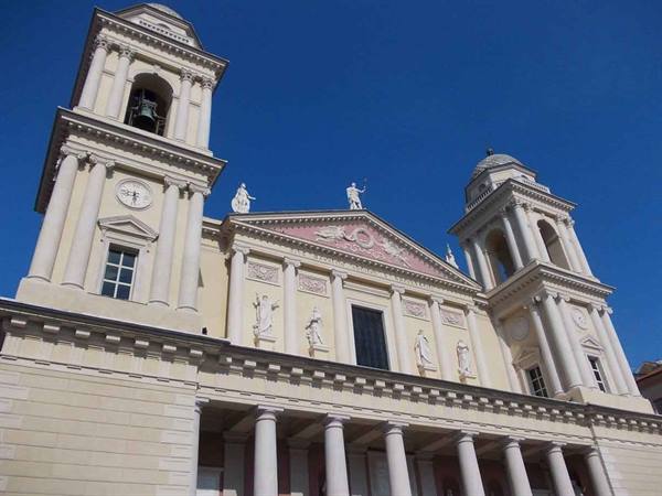 Neoclassical facade with twin bell towers, statues and columns under blue sky
