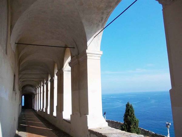 Stone loggia with white arches opening onto the deep blue sea