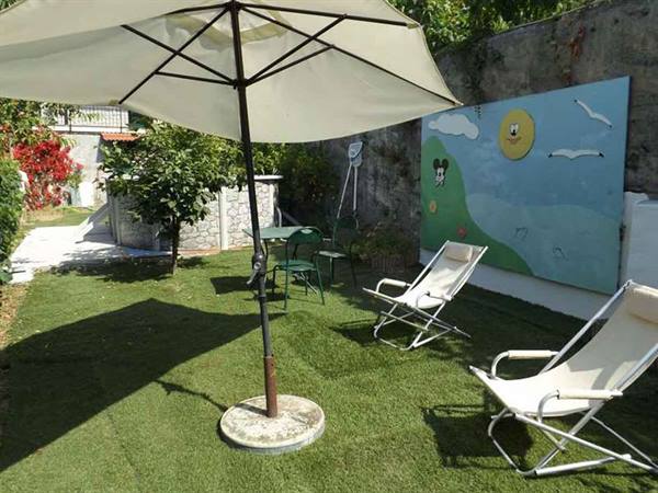 Sun umbrella and deck chairs on artificial grass, wall painted with Mickey Mouse and sun