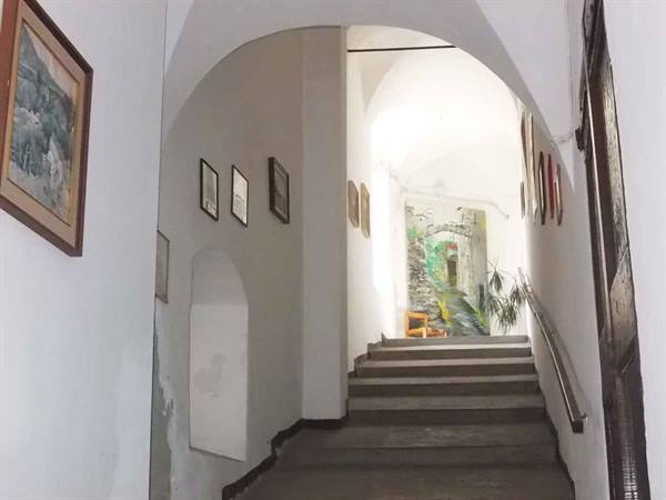 Interior staircase under white arch, framed pictures and bright mural at the end