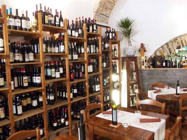 Wooden shelves full of wine bottles in the wine bar restaurant with stone vaults
