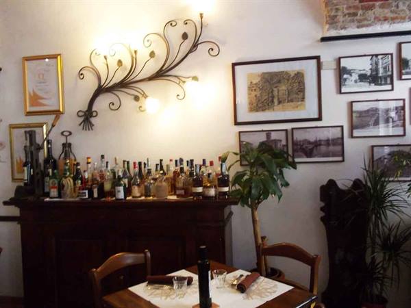Wine bar with bottles on wooden sideboard, wrought iron lamp and vintage photos on walls