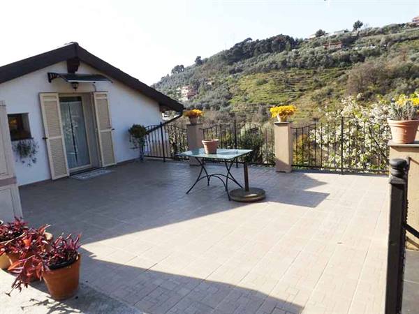 Tiled terrace with wrought iron table, mimosa pot, cultivated hills behind the house