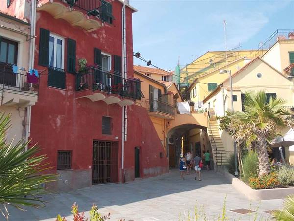 Tourists walk past colorful houses and an arch in Sestri Levante village