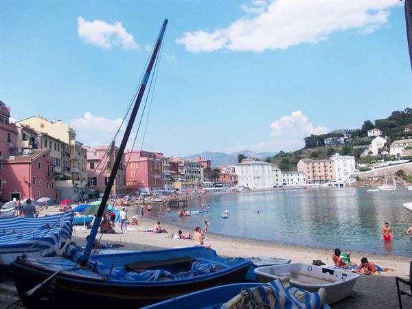 Blue boats beached on the sand, swimmers in Sestri Levante bay