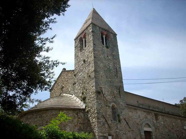 Ancient Romanesque stone church with bell tower and apse among trees