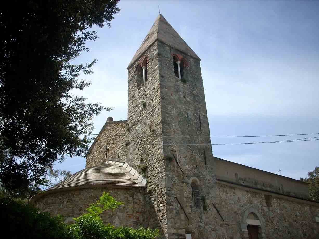 Antica chiesa romanica in pietra con campanile e abside tra gli alberi