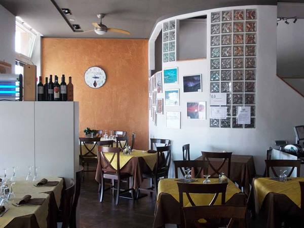 Restaurant dining room with set tables, yellow tablecloths, wine bottles and glass blocks