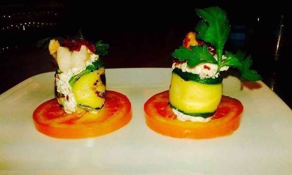 Grilled zucchini rolls with ricotta on tomato slices, garnished with parsley