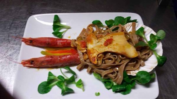 White plate with squid-ink noodles, prawns, scallop shell and greens