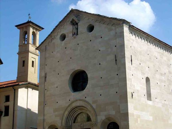 Light stone facade of Cividale Cathedral with round window and bell tower