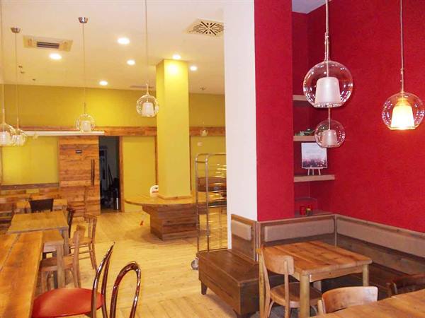 Café interior with wooden tables, benches and clear glass pendant lamps
