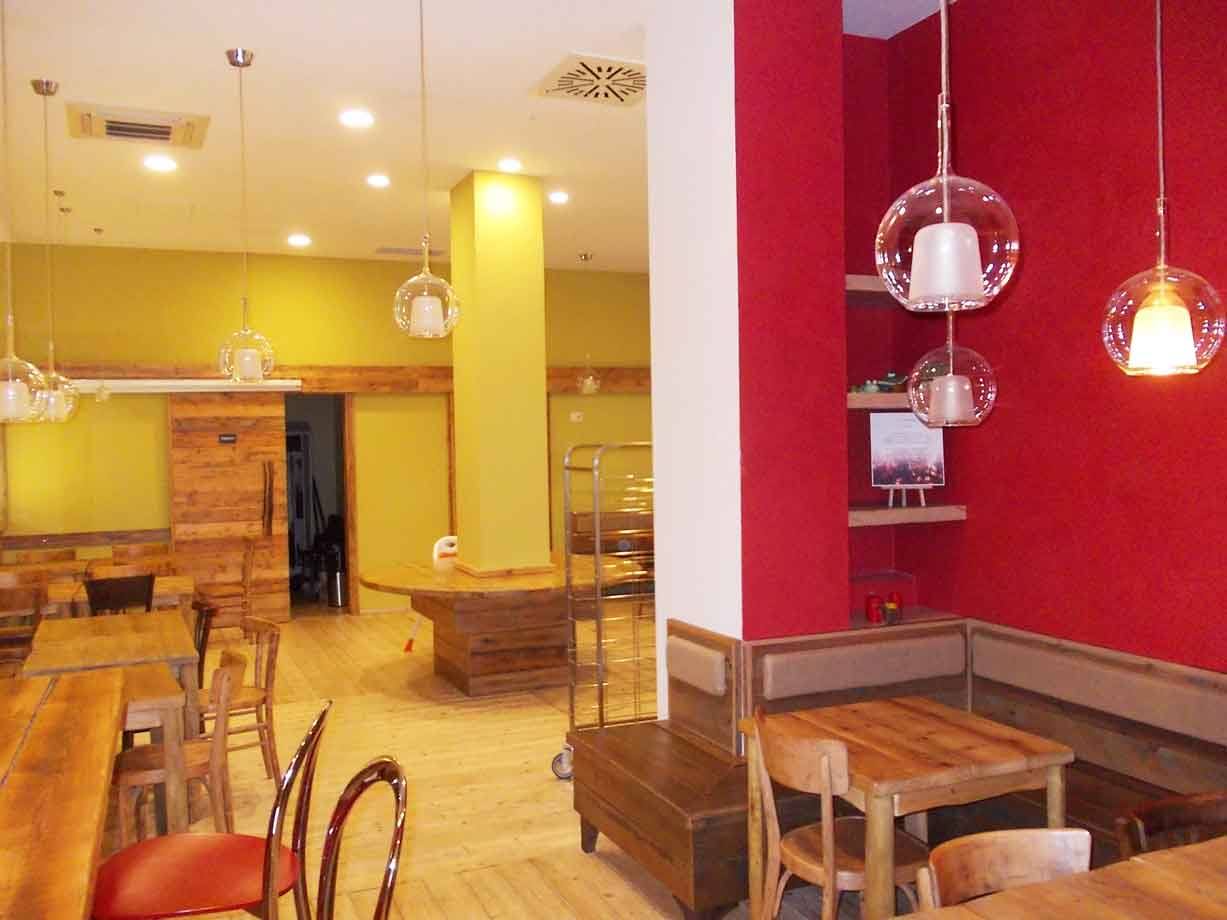 Sala di bar con tavoli in legno, panche e lampade a sospensione trasparenti