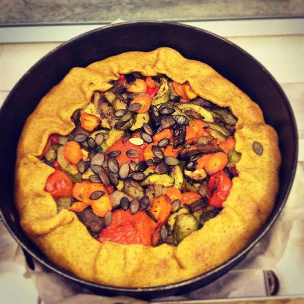 rustic vegetable galette with roasted peppers and pumpkin seeds in a black pan