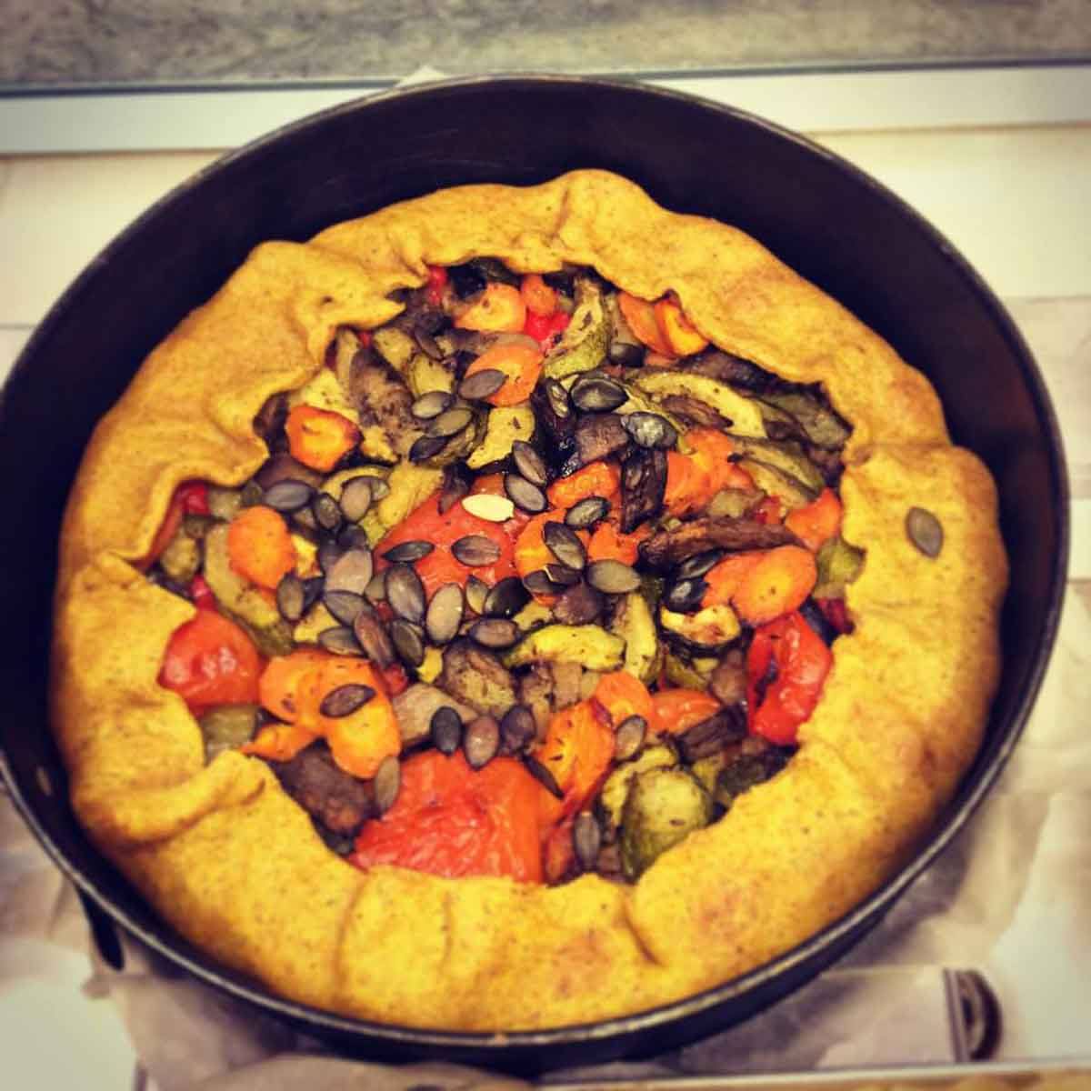torta salata di verdure arrostite e semi di zucca in teglia nera