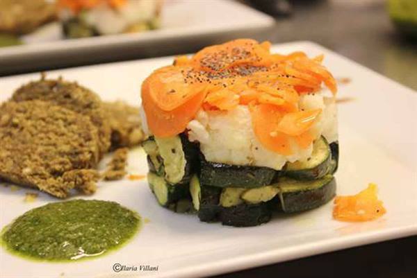 Zucchini and rice stack with carrots, veggie burger and green sauce on white plate