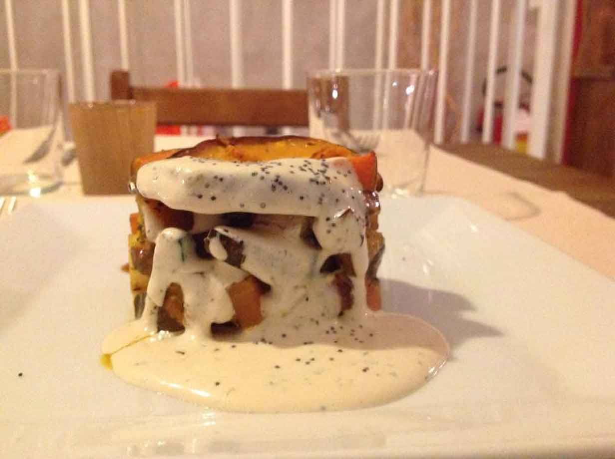 Tortino di verdure con salsa cremosa servito su piatto bianco in trattoria