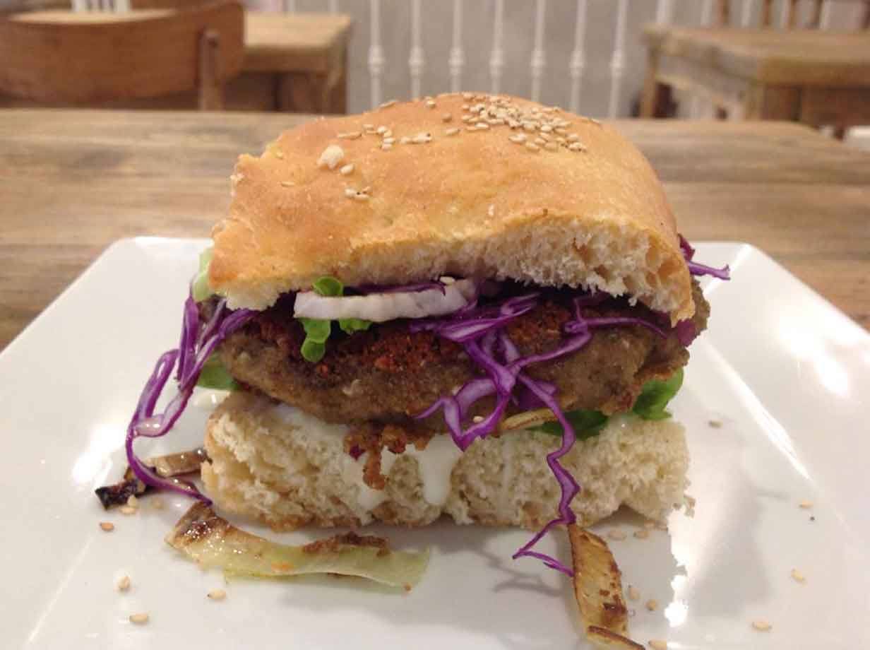 Hamburger con pane ai semi, cavolo viola e cipolla su piatto bianco