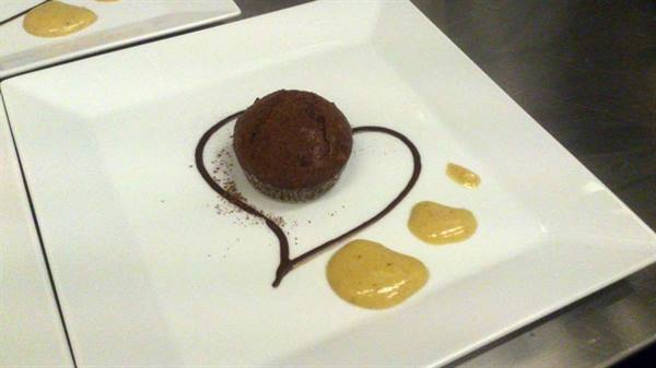 Chocolate muffin on white plate with chocolate heart and yellow sauce