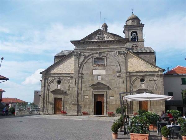 Stone church with bell tower by the square, café umbrella in front