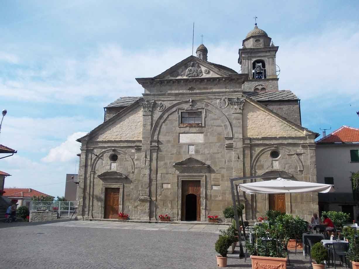 Chiesa in pietra con campanile sulla piazza, ombrellone del bar davanti