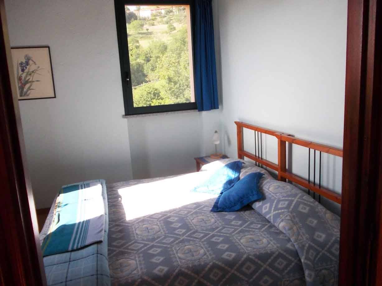 Camera con letto a castello in legno, luce solare e finestra aperta sulla collina