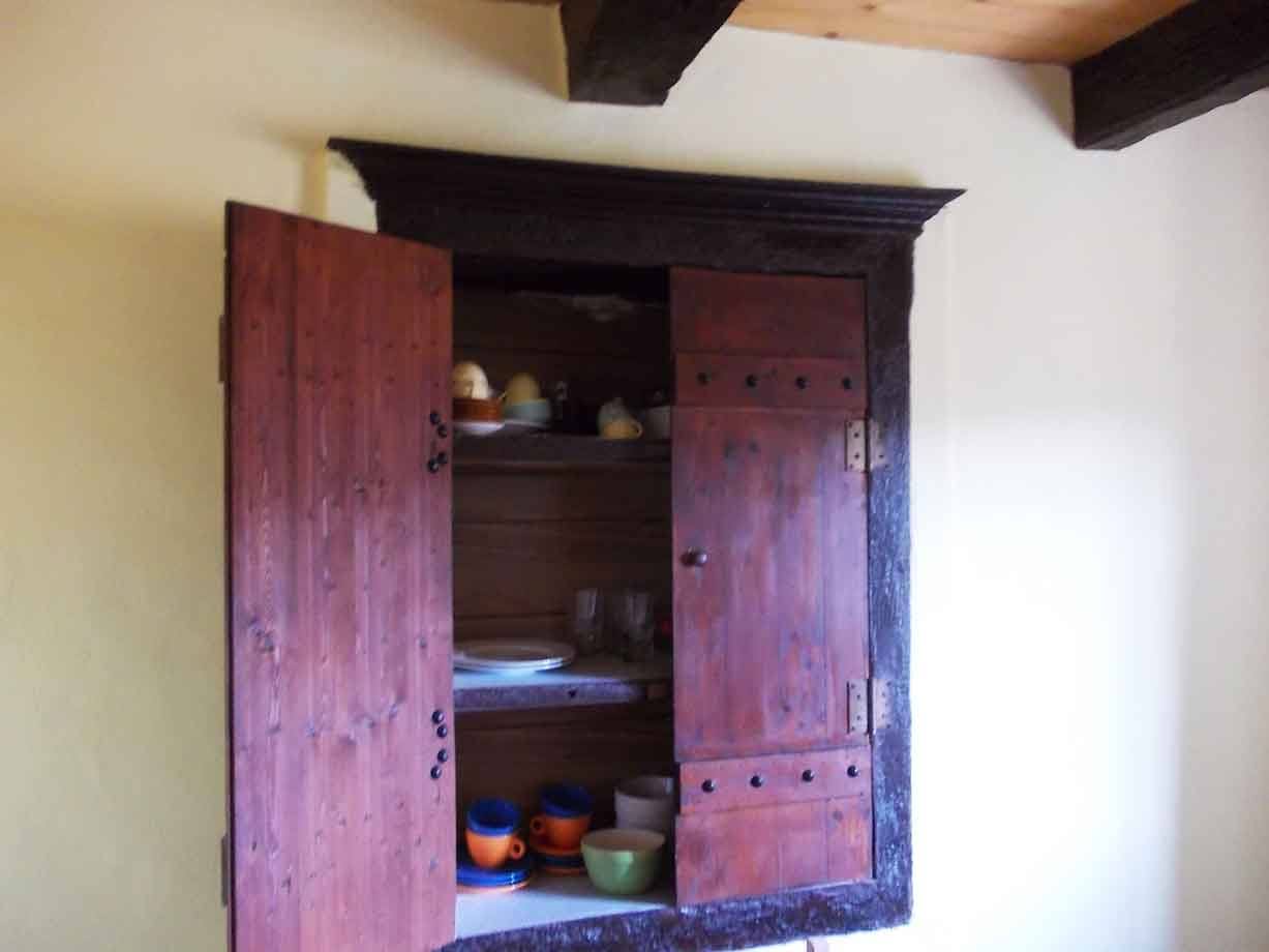 Antica credenza in legno rosso con stoviglie, travature sul soffitto