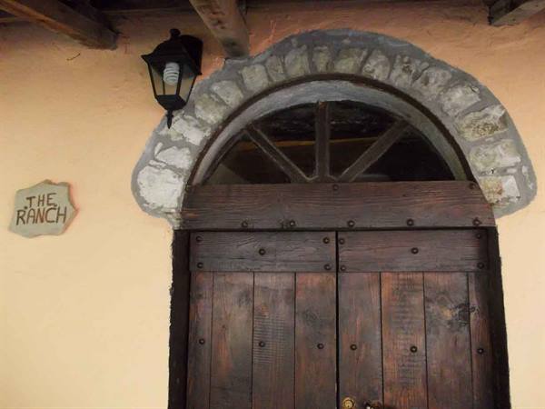Wooden door with stone arch and lantern, The Ranch sign