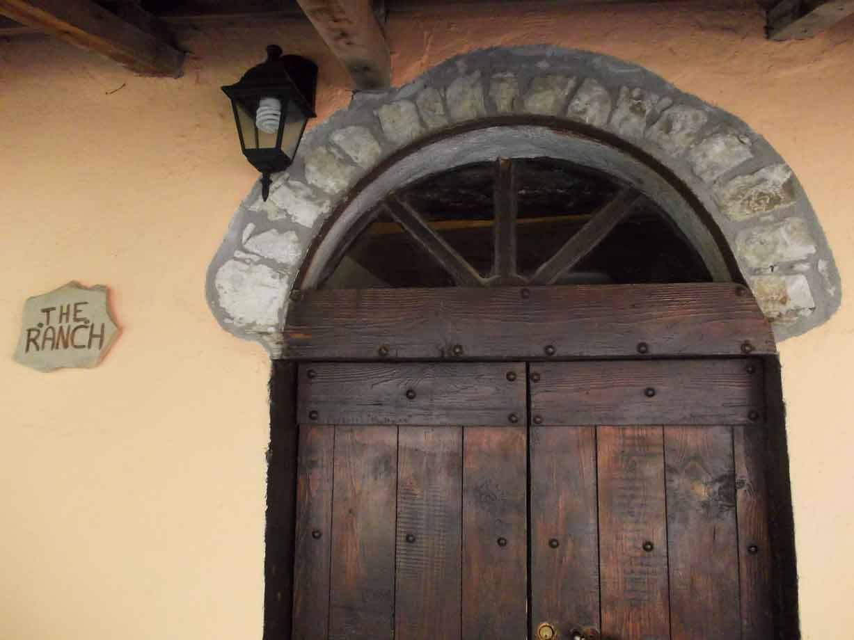 Porta in legno con arco di pietra e lanterna, insegna The Ranch