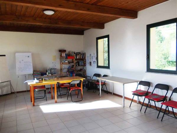 Room with wooden tables, black chairs, whiteboard and books, sunlight from the window