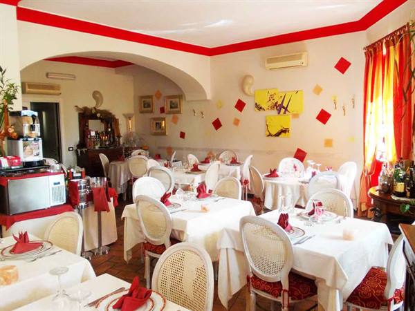 Restaurant dining room set with white tablecloths, wicker chairs and red decorations