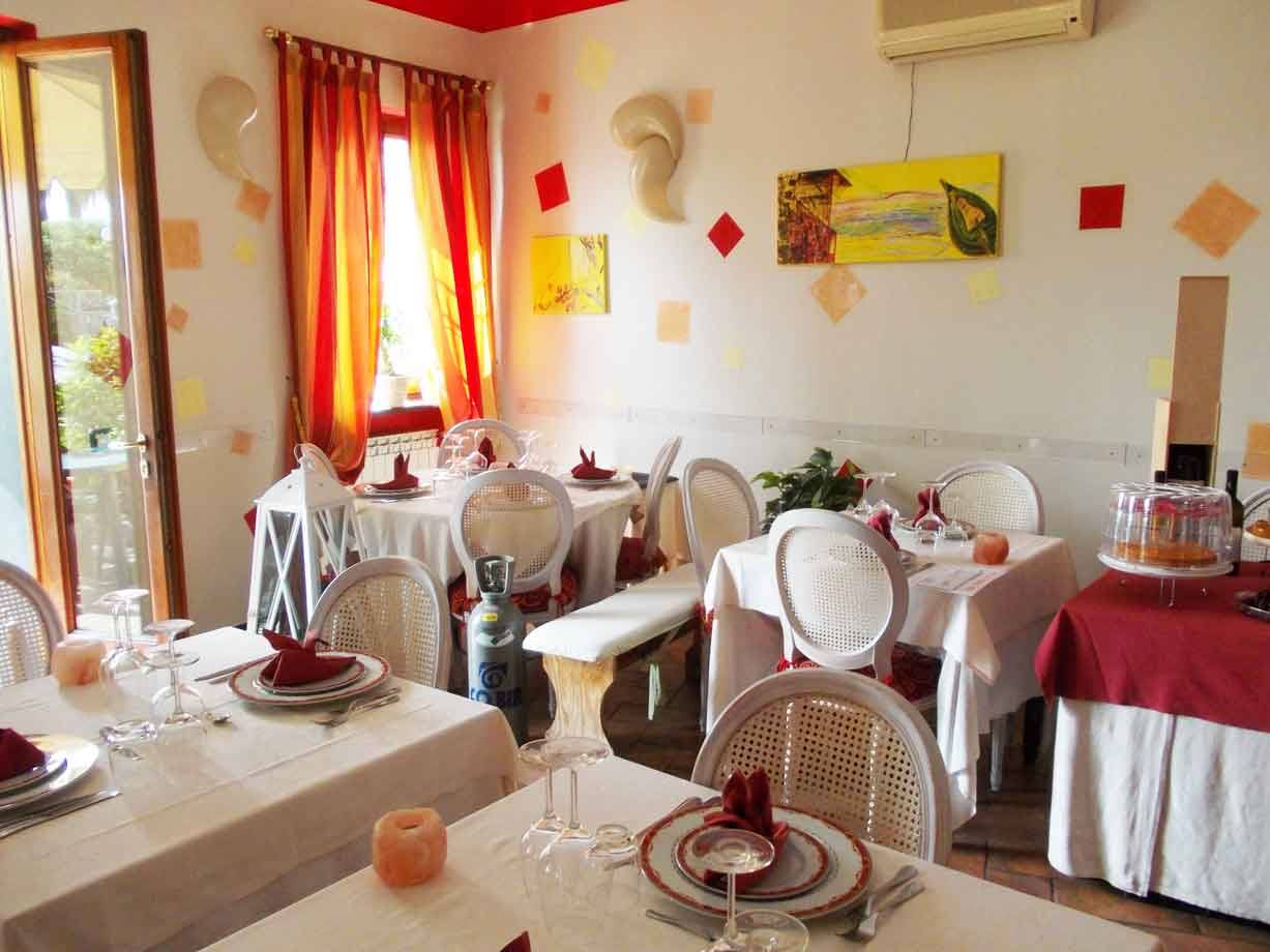 Sala ristorante con tavoli apparecchiati, tovaglie bianche, sedie bianche e tende arancioni