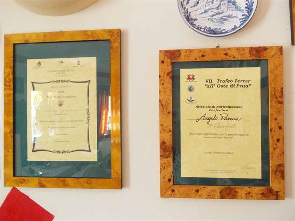 Two framed certificates in burl wood hang on the wall beside a decorative plate