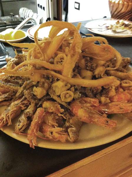Fried mixed seafood platter with shrimp and calamari, lemon on table
