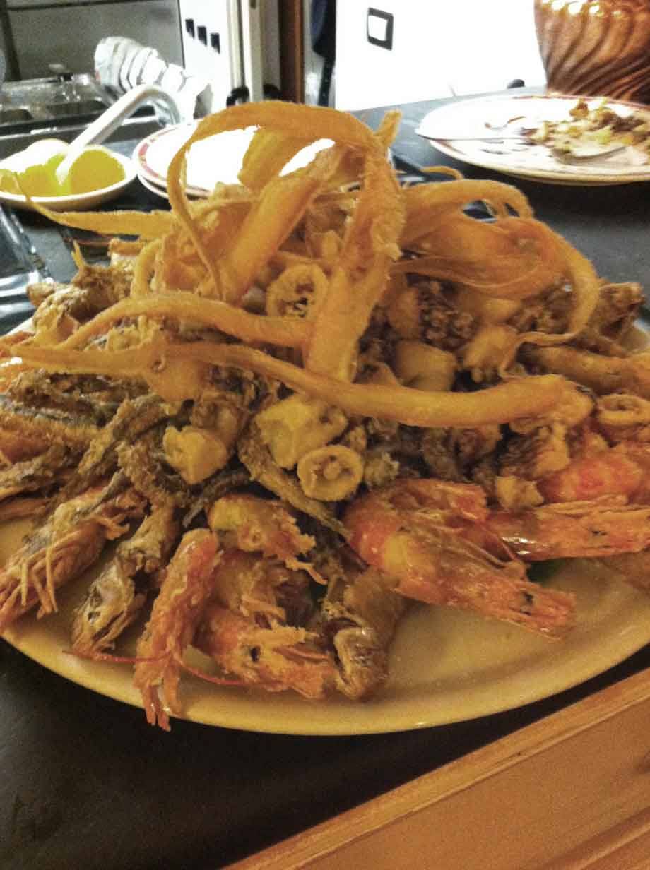 Piatto di fritto misto con gamberi, calamari e totani, limone sul tavolo