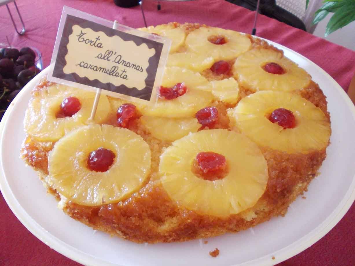 Torta all'ananas caramellata con ciliegie, cartello scritto a mano, su tovaglia rossa