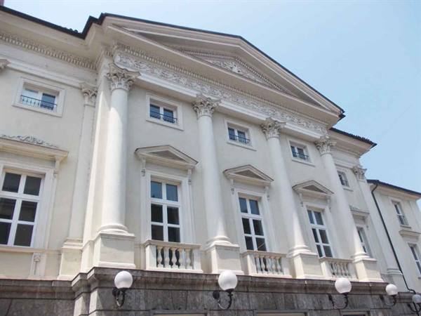 White neoclassical facade with Corinthian columns and pediment against blue sky