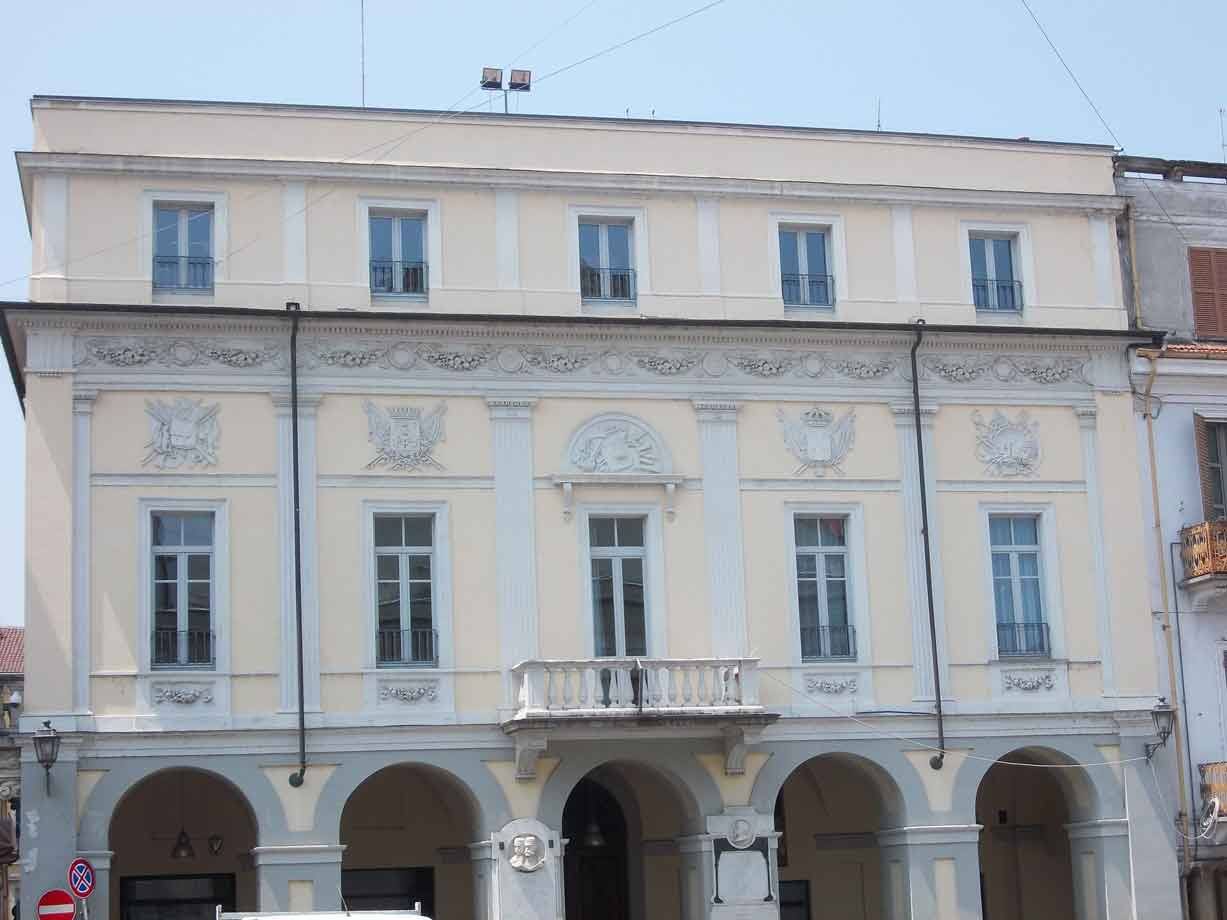 Palazzo giallo con archi, stemmi scolastiti e balcone in pietra
