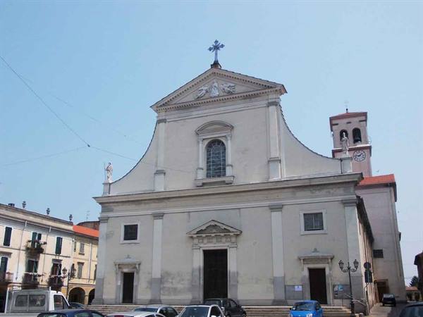 White church with classical facade and bell tower, cars parked on the square