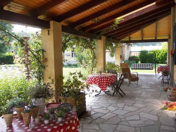 Wooden porch with stone floor, red polka-dot tablecloths and potted plants