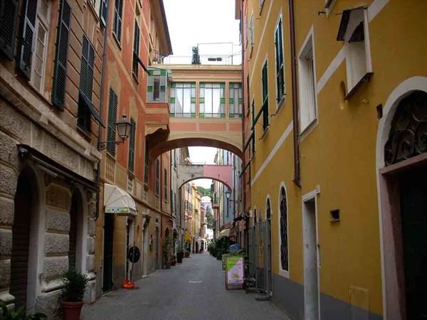 Street with ochre and pink painted arches in Genoa, soft light