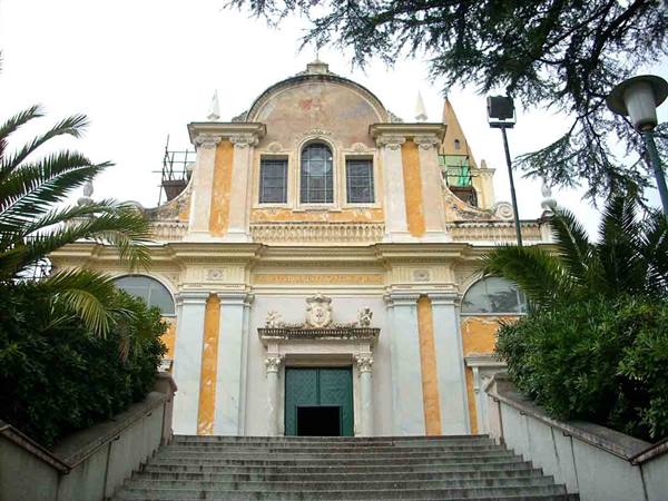 Ochre baroque church with staircase and palms, frescoed facade