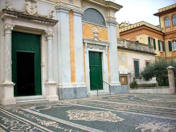 Baroque church with green doors and decorative white pebble mosaic floor