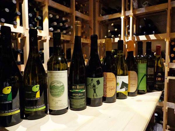 Wine bottles lined up on wooden counter in a lit cellar