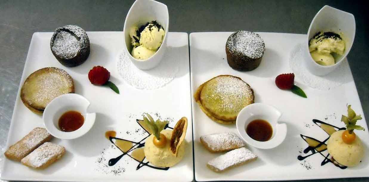 Due piatti bianchi con tortini al cioccolato, gelato, lamponi e biscotti