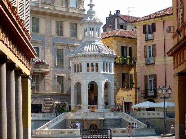 La Bollente in Acqui Terme, white marble pavilion among colorful buildings