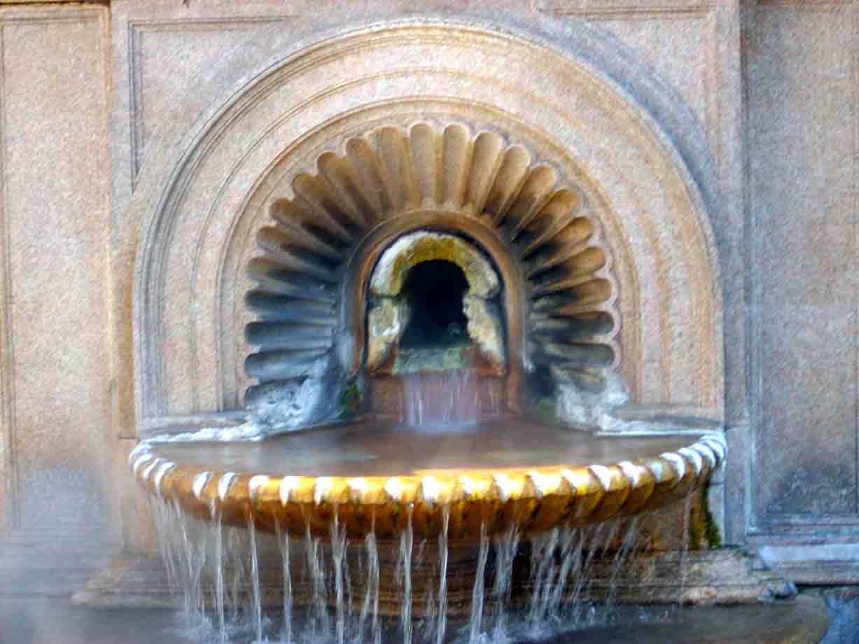 Fontana in pietra con conchiglia scolpita, acqua che trabocca dalla vasca marrone