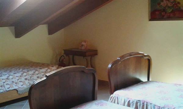Attic bedroom with two dark wooden beds, soft light, floral painting