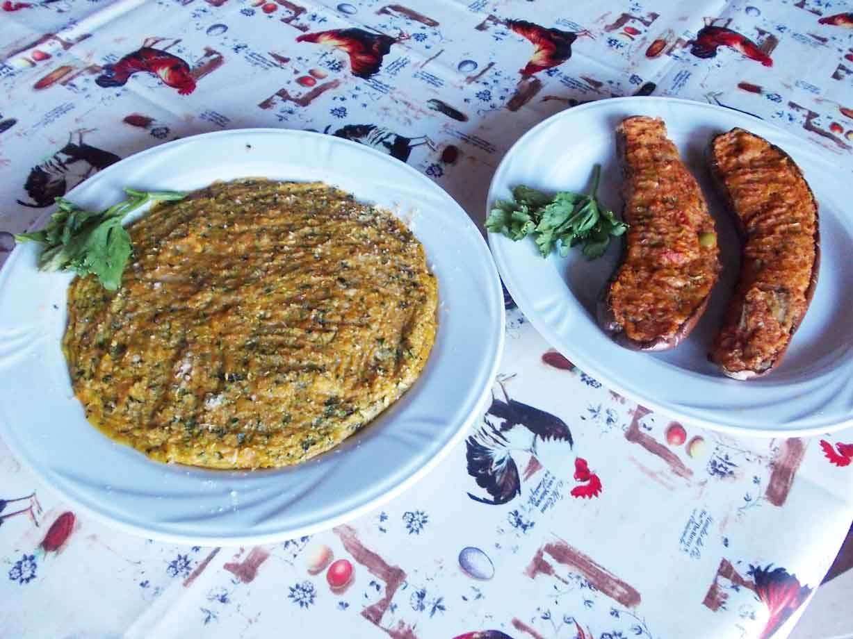 Frittata erbosa e melanzane ripiene su piatti bianchi, tovaglia stampata