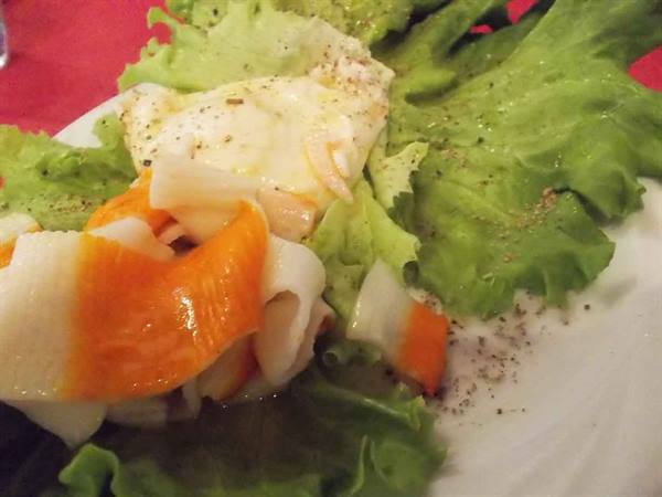 Salad with surimi sticks and egg on white plate